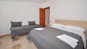 A bedroom with two single beds, a wooden door, and a nightstand. - Apartments Cetara (Cetara)