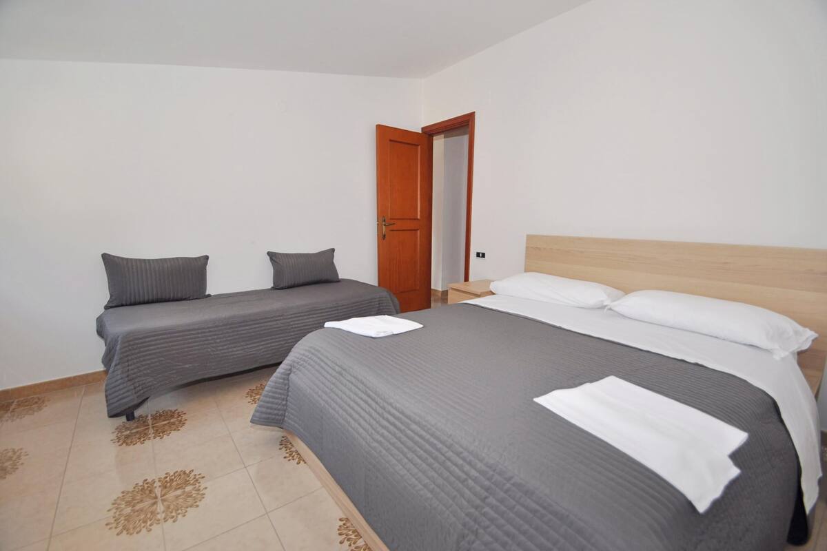 A bedroom with two single beds, a wooden door, and a nightstand.