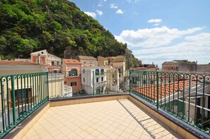 Una terraza en la azotea con suelo de baldosas y barandilla de metal verde.