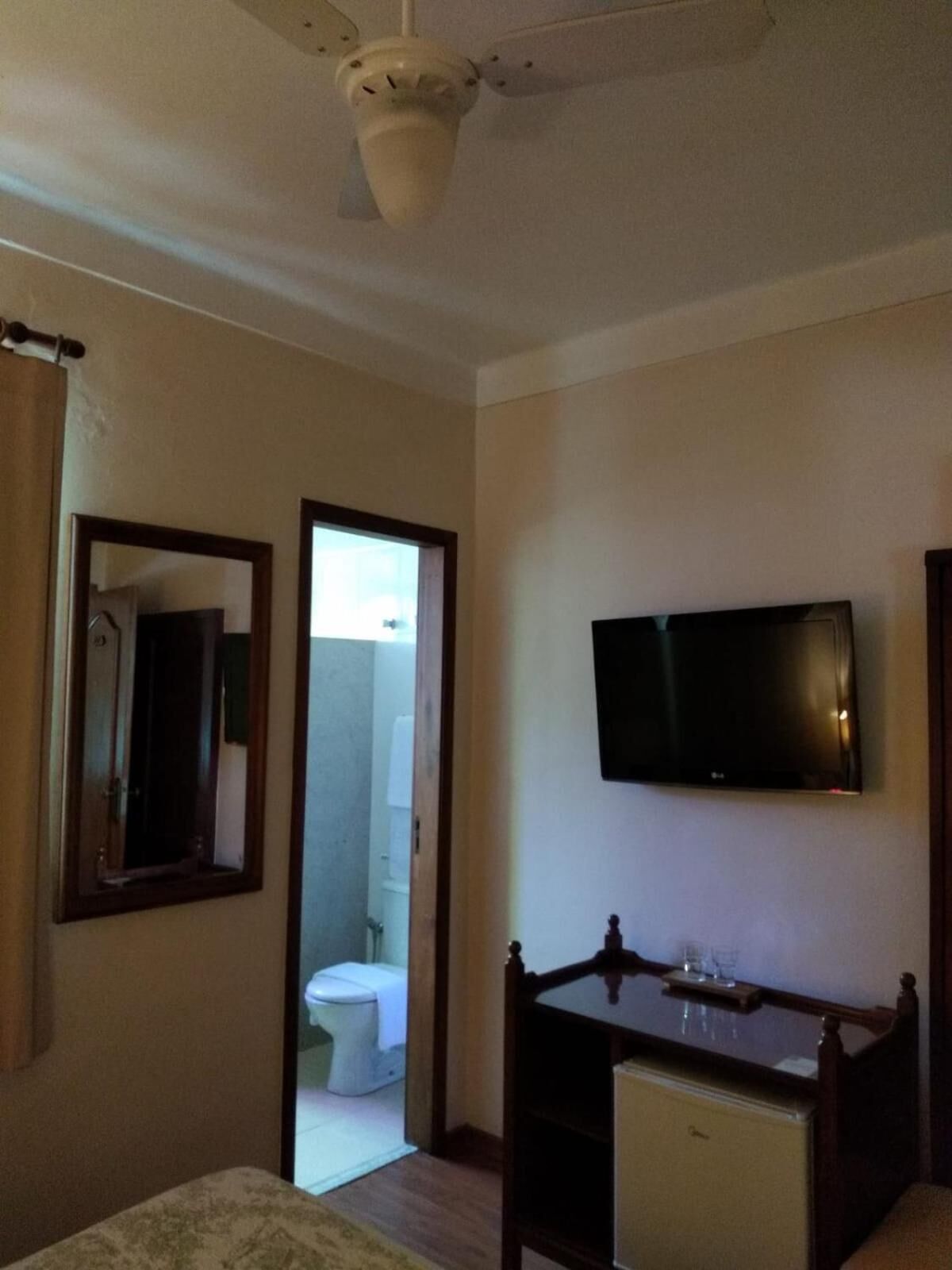 Ein Schlafzimmer mit Bett, Schreibtisch, Fernseher und einem durchgegangenen Tür erkennbaren Badezimmer.