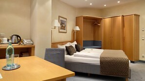 A hotel room with a bed, bedside table, lamp, and wardrobe. - Hotel Russmann (Goldbach)