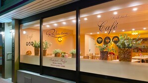 A café with a large window display featuring the name 'Frühsticks-Buffet' and a reservation number. - Hotel Russmann (Goldbach)