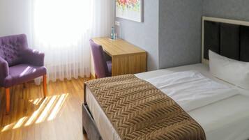 Une chambre d’hôtel avec un lit, un bureau, une chaise et un tableau au mur.