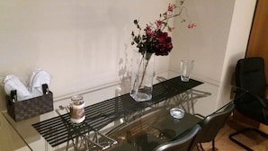 Una mesa de vidrio con un florero, un vaso y una vela.
