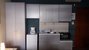 Una cocina compacta con cafetera, lavamanos y microondas.