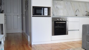 Una cocina compacta con microondas, horno y lavabo.