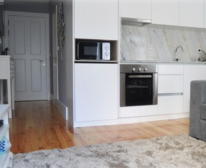 Una cocina compacta con microondas, horno y lavabo.