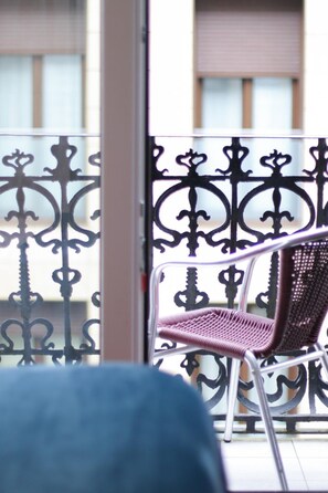 A chair on a balcony with a decorative metal railing. - Pension Yoldi (San Sebastián)