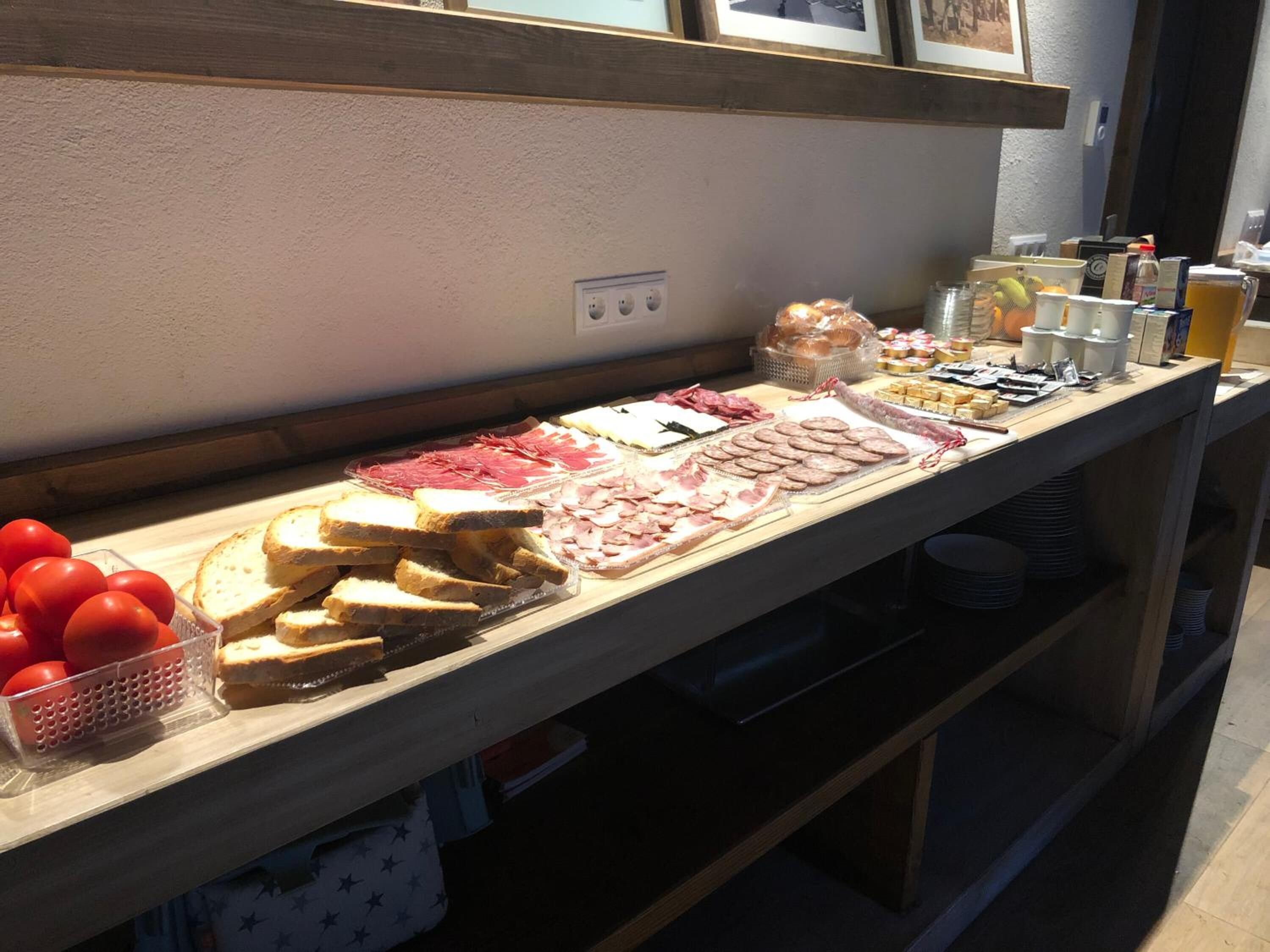 Une table de buffet proposant divers aliments, notamment du pain, de la viande et des tomates.