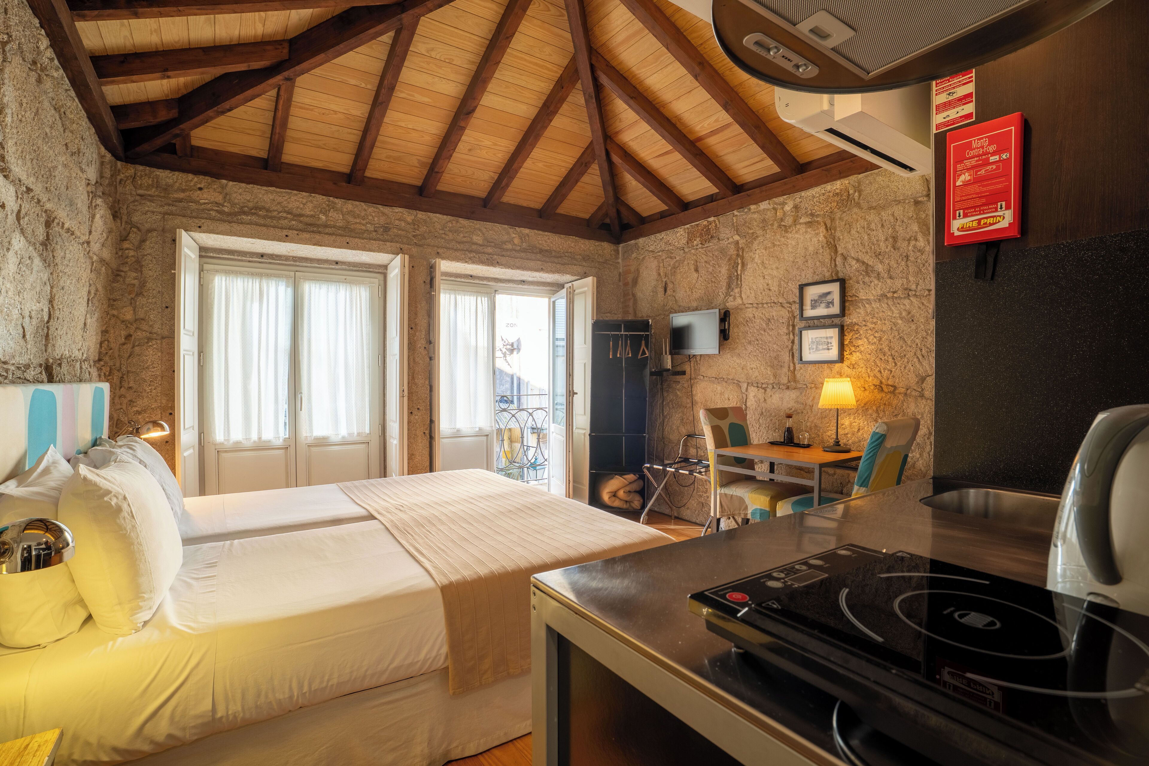 A cozy room with a bed, a table with a lamp, a TV, and a fireplace.
