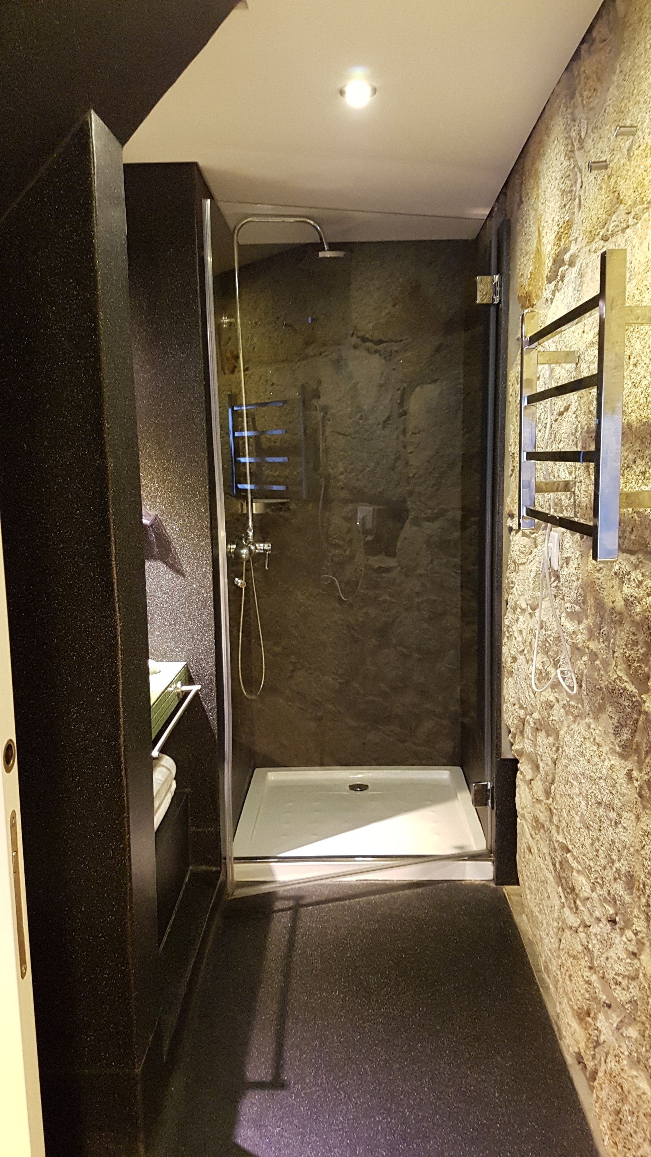 Ein modernes Badezimmer mit einer gläsernen Duschkabine, einem integrierten Waschbecken und einem Handtuchhalter.