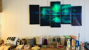A breakfast buffet with various food items and beverages, and a wall with five paintings of landscapes.