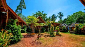Un resort con cabañas de madera rodeadas de exuberante vegetación y palmeras.