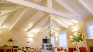 Een hotelkamer met een hoge plafond, houten balken, een schilderij aan de muur en een kitchenette.