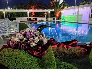 A pool area with lounge chairs and a decorative floral arrangement. - Hotel Palazzo Giancola (San Severo)