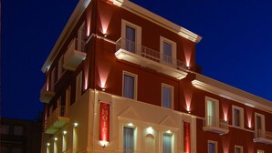 Een meerlaags hotel met balkons, een rode gevel en verlichte borden die aangeven dat het een hotel is.