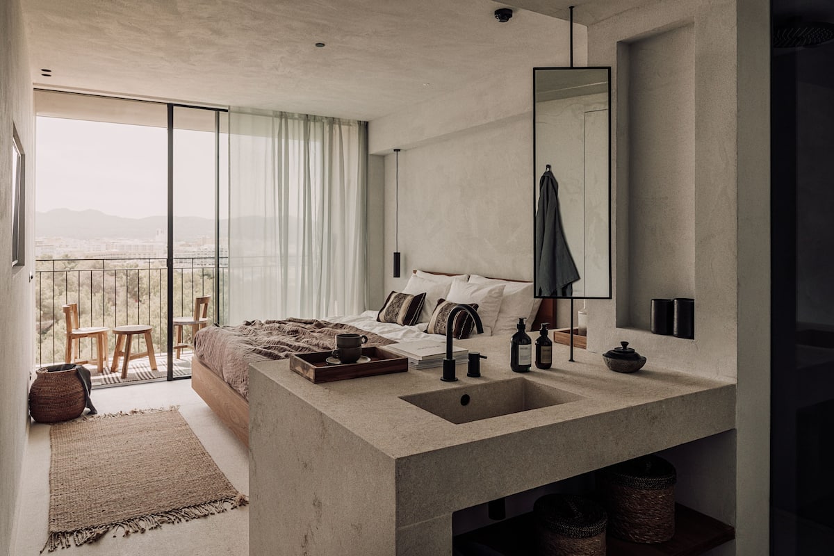 Un dormitorio moderno con una cama grande, un lavamanos empotrado y un balcón con vistas.