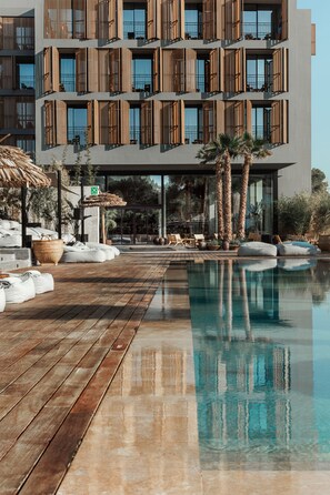 Un hôtel moderne doté d’une piscine, d’une terrasse en bois et de chaises longues.