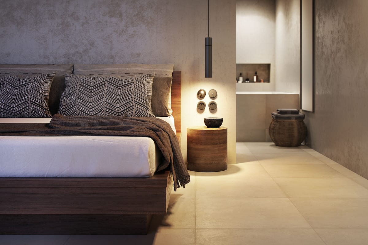 Un dormitorio moderno con una cama de madera, una mesita de noche con un cuenco, y una lámpara colgante.