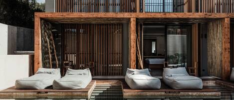 A modern outdoor pool area with wooden loungers and a view of a building with vertical wooden slats.
