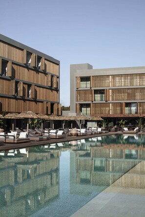 Un hotel moderno con piscina, sillas de descanso y sombrillas.