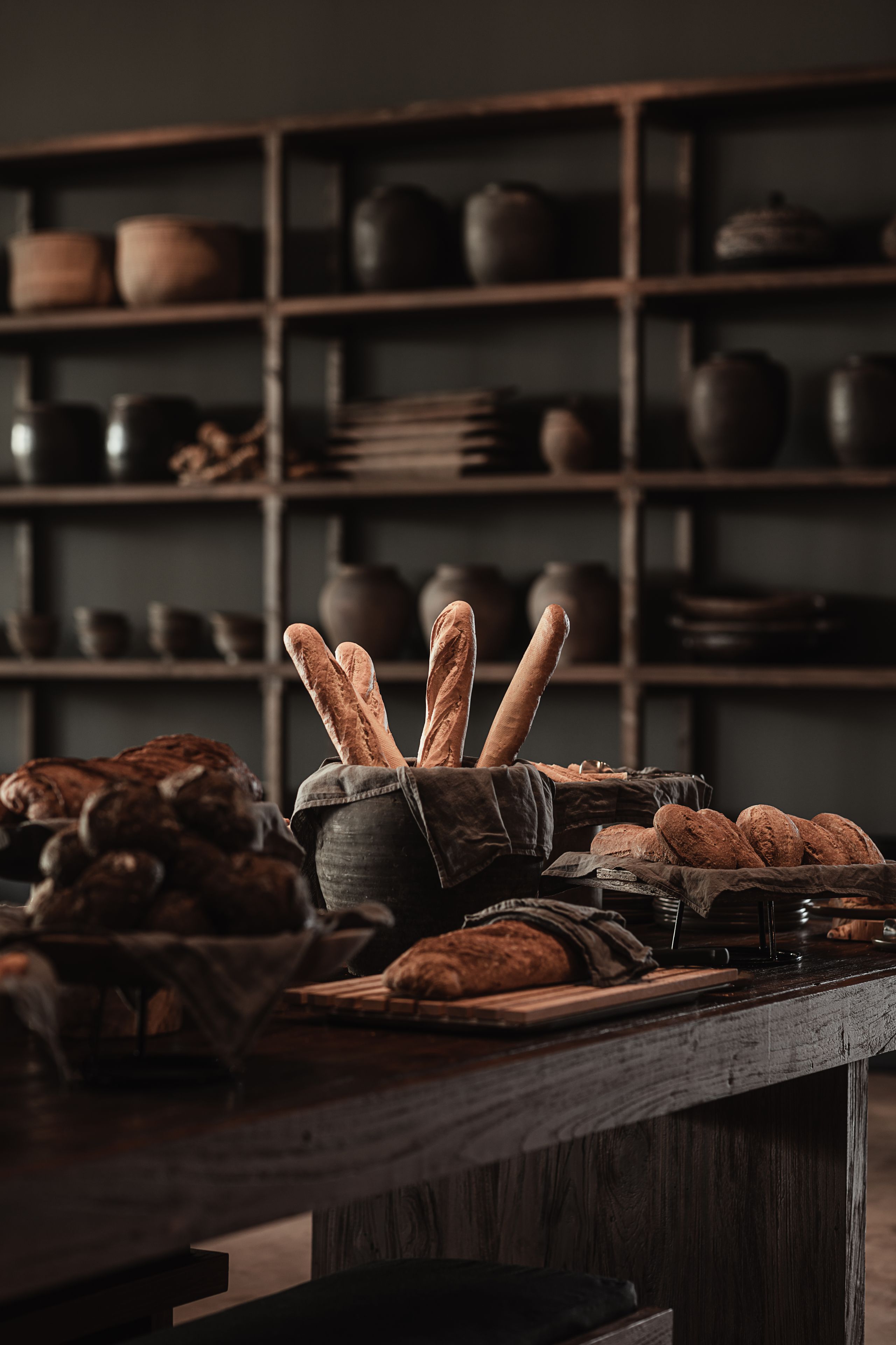 A rustic kitchen with wooden shelves holding various kitchenware.