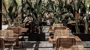 Un área de estar al aire libre con mobiliario de mimbre y lámparas colgantes bajo un techo de madera.
