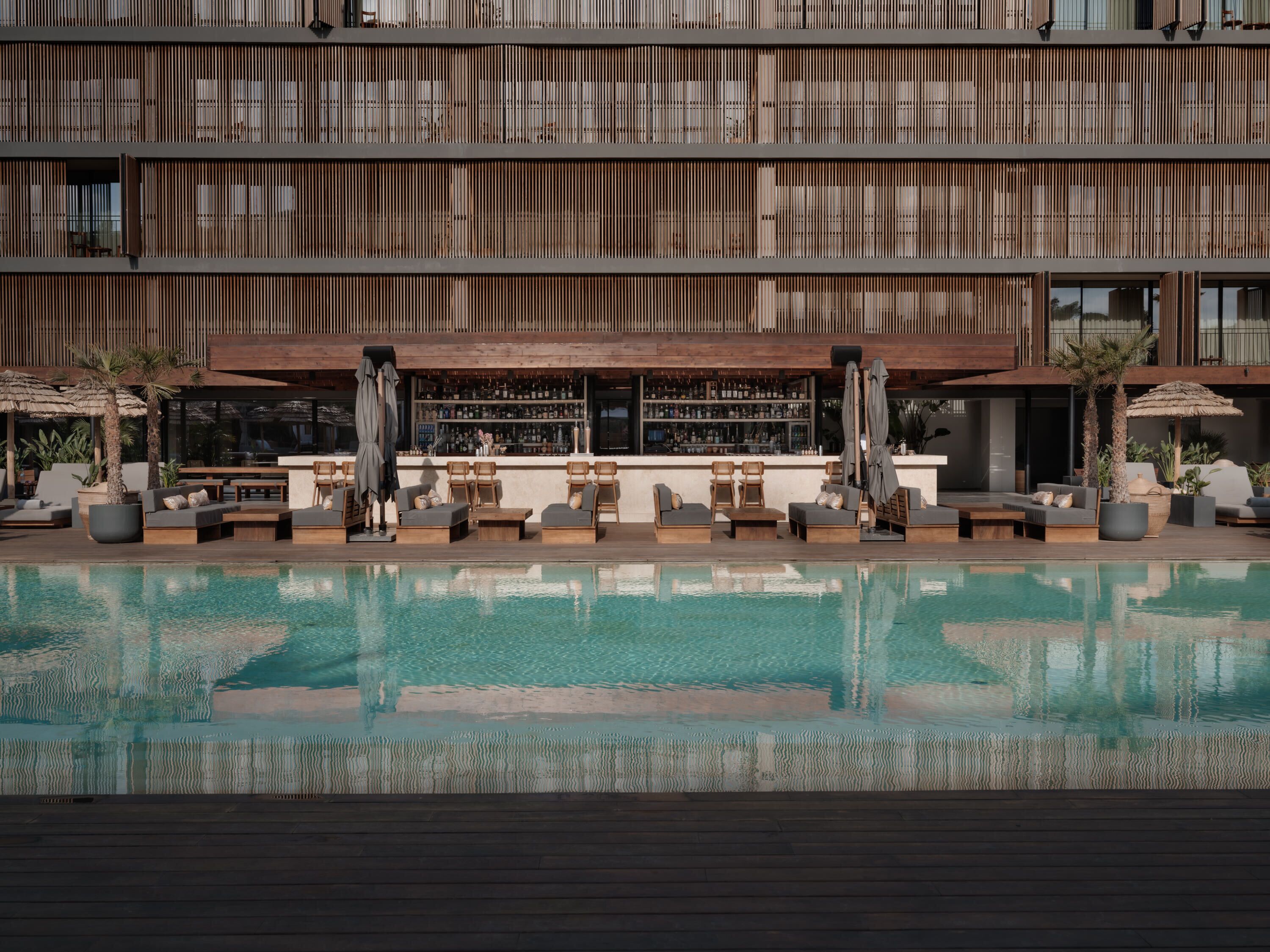 A poolside area with lounge chairs, a bar, and a wooden facade.