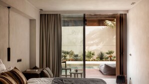 Un dormitorio moderno con una cama grande, una mesita de noche y vistas a una piscina y plantas de exterior.