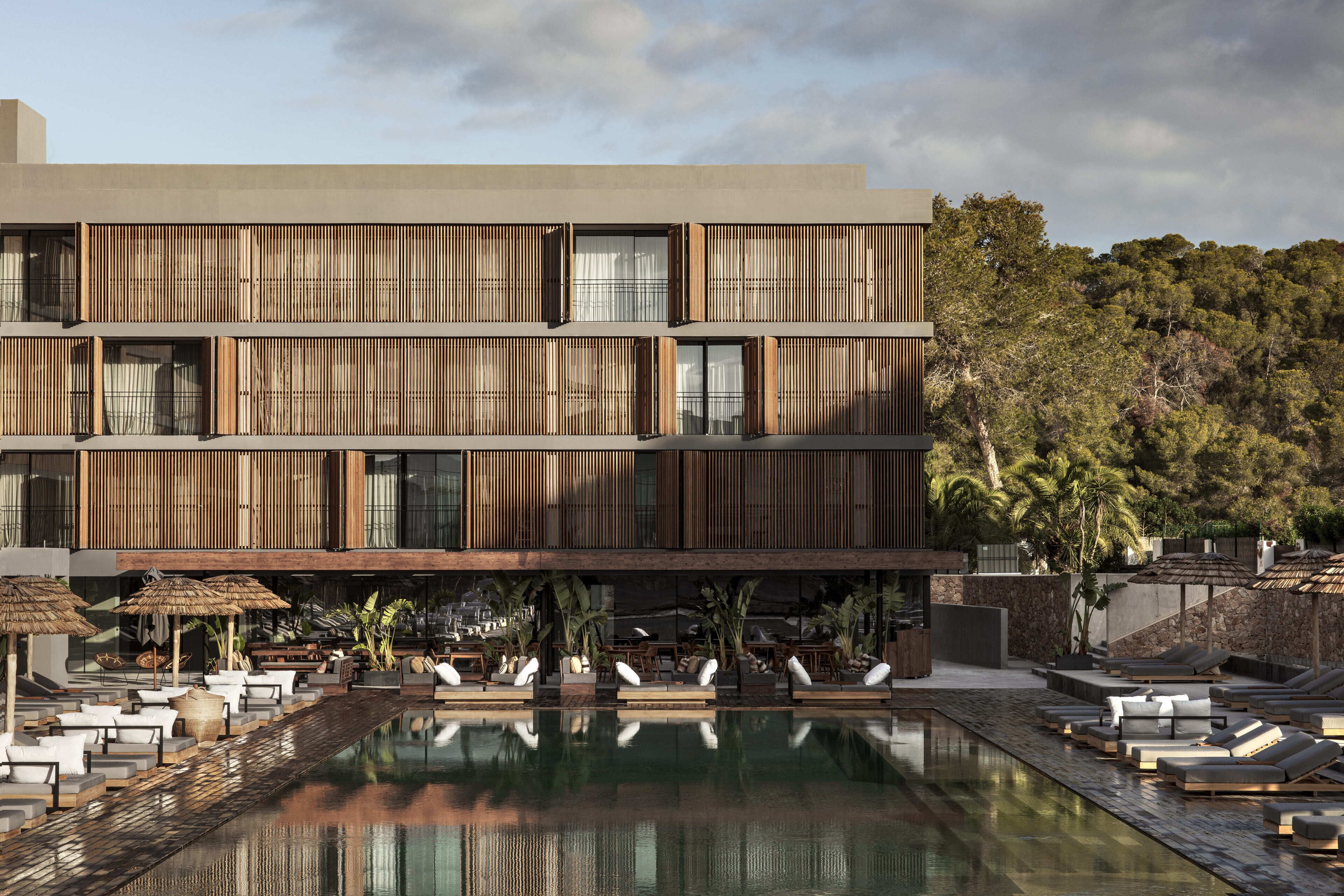 A modern building with a pool, lounge area, and outdoor seating.
