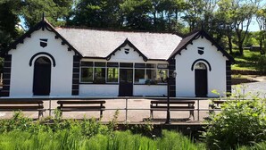 A white building with black trim and a peaked roof, featuring a central glass window and two doors. - The Ritz House (Lisdoonvarna)