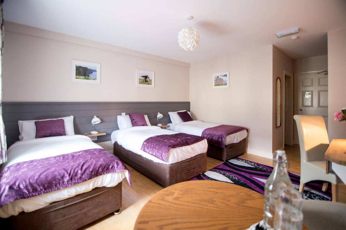 Ein Hotelzimmer mit zwei Betten, einem runden Holztisch und einem Stuhl.