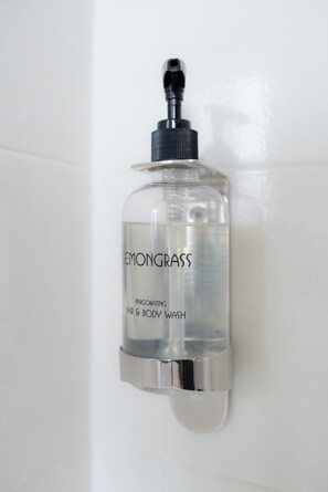 A clear bottle of Lemongrass invigorating hair and body wash mounted on a white wall.