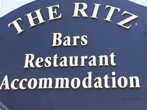 A sign for "The Ritz Bars Restaurant Accommodation" with a dark background and gold lettering.