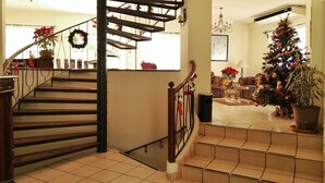 Eine Treppe mit Holzhandlauf und Geländer, die in ein Wohnzimmer mit Weihnachtsbaum und Sofa führt.