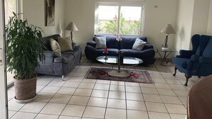 Ein Wohnzimmer mit einem blauen Sofa, einem runden Couchtisch, einer Topfpflanze und einer Chandelier.