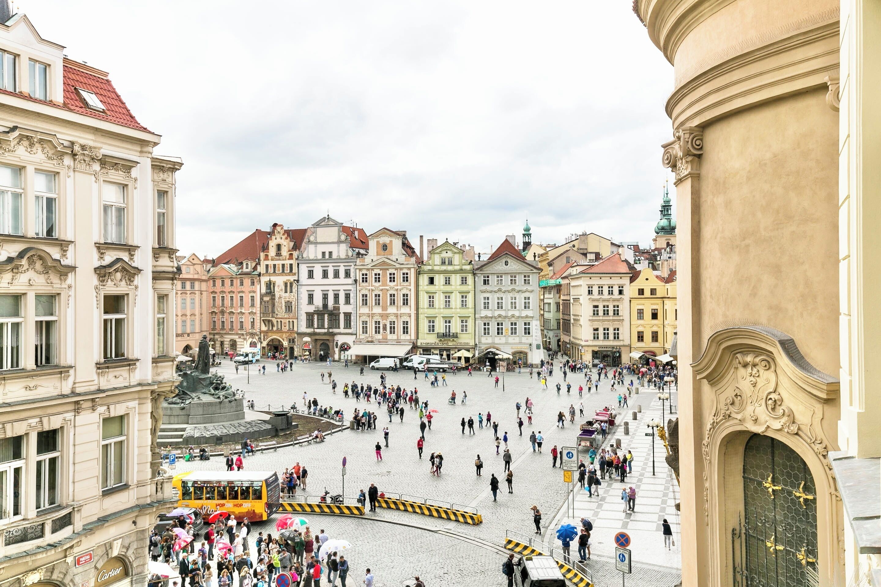 A bustling square with historic buildings, a central fountain, and a tram.