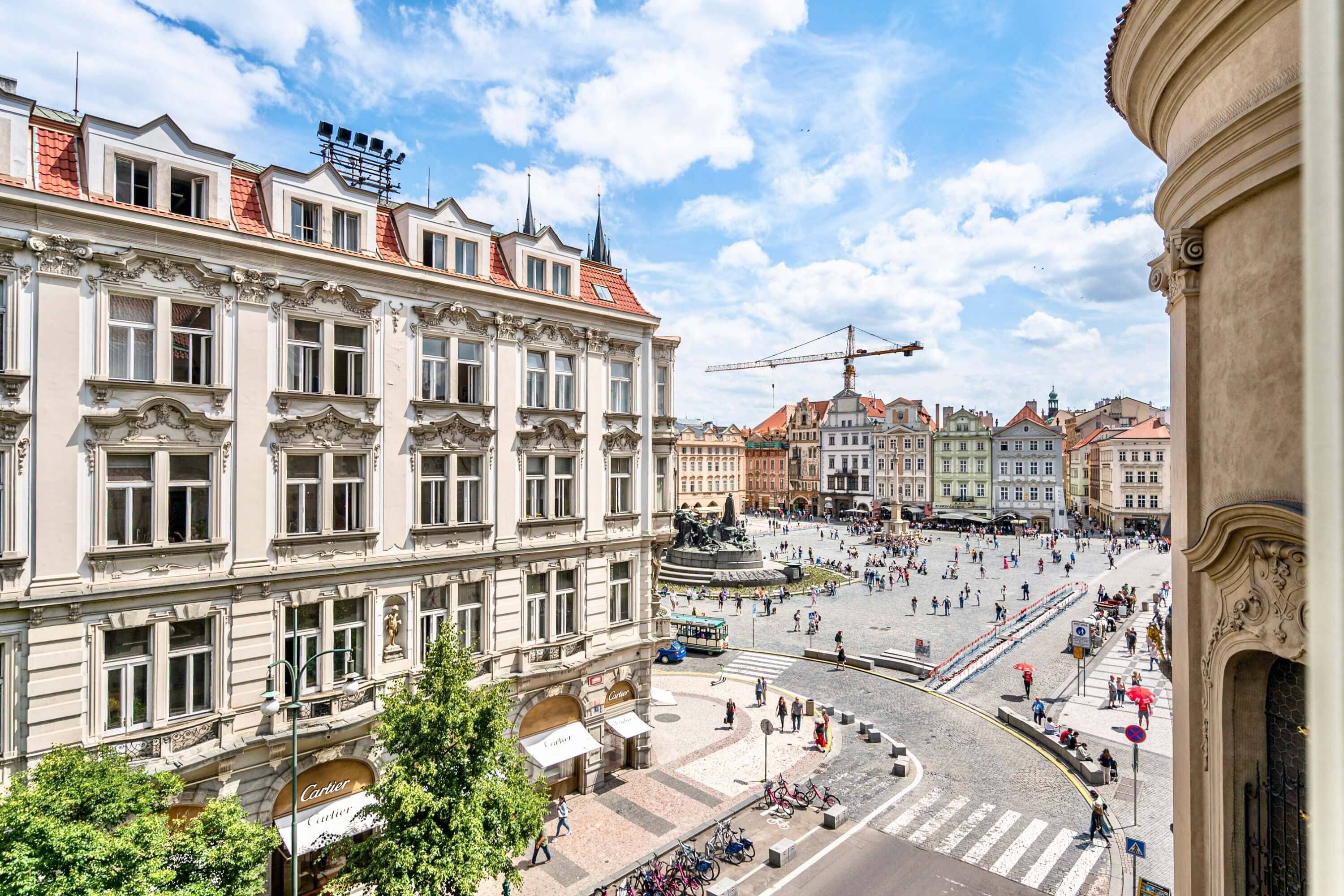 A historic square with ornate buildings, a central fountain, and a busy pedestrian area.