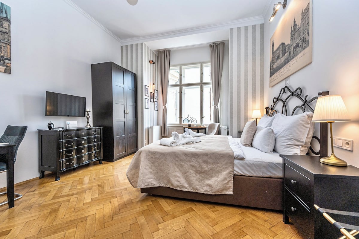 A modern hotel room with a large bed, a desk, a wardrobe, and a television.