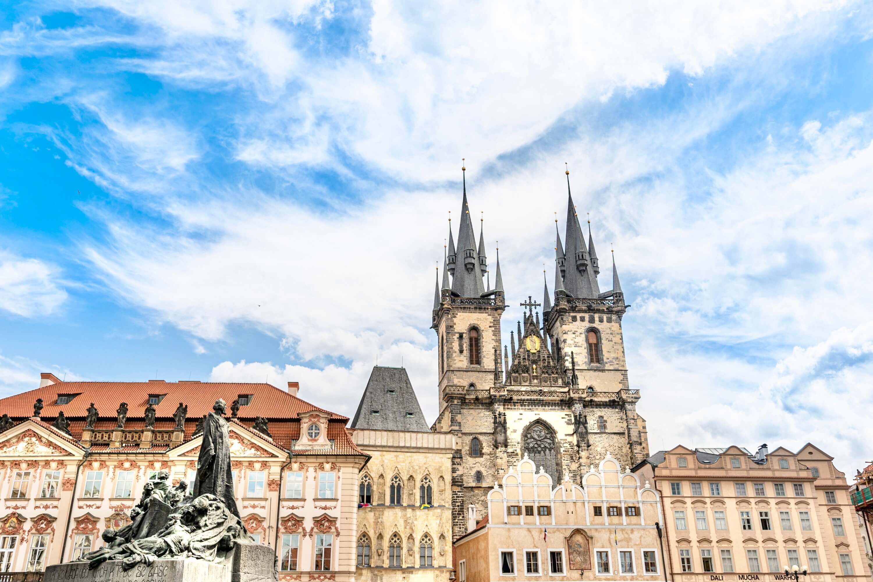 A historic building with a prominent tower and statues in front.
