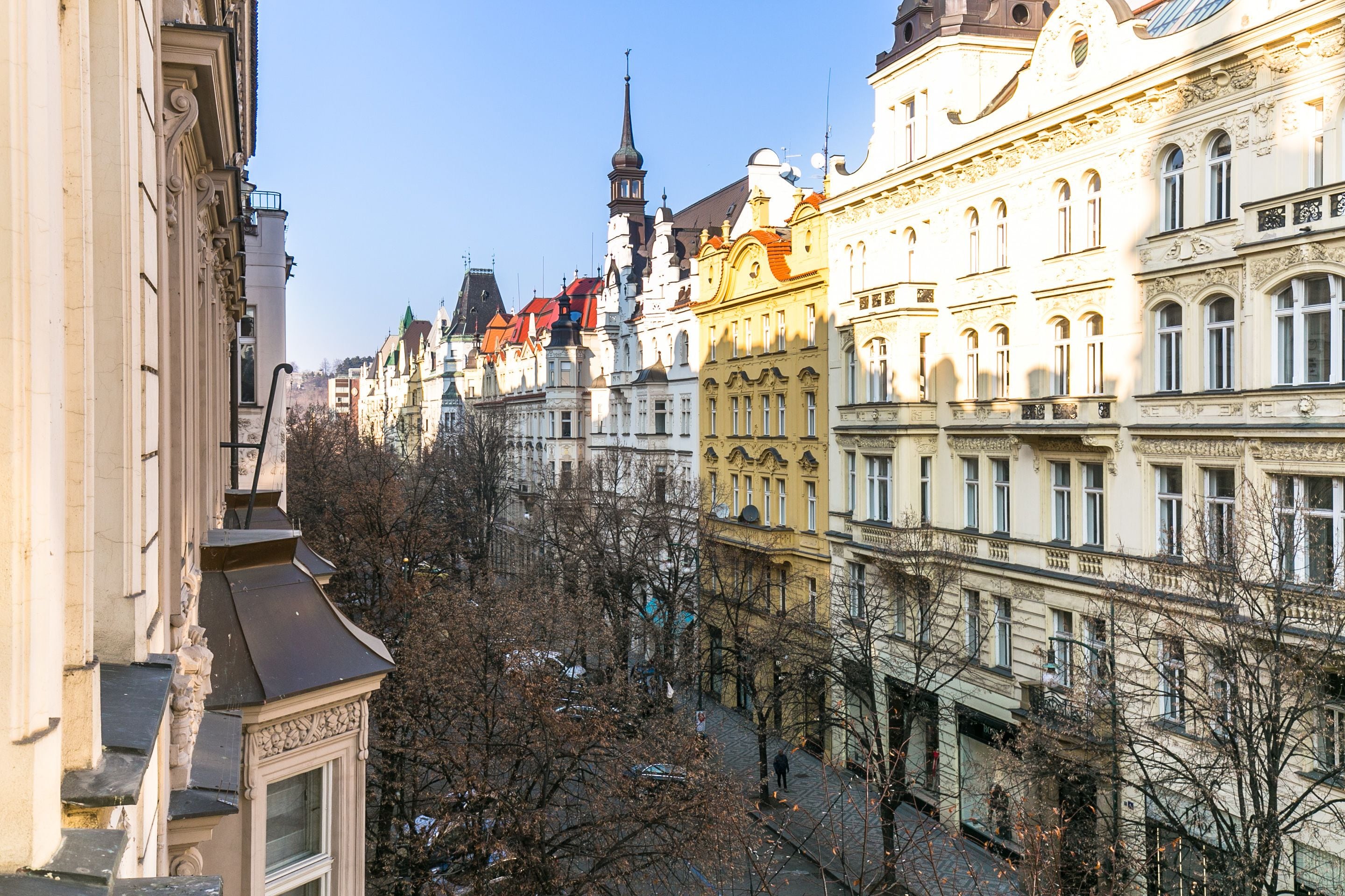 A row of historic buildings with ornate facades and a prominent church steeple in the background.