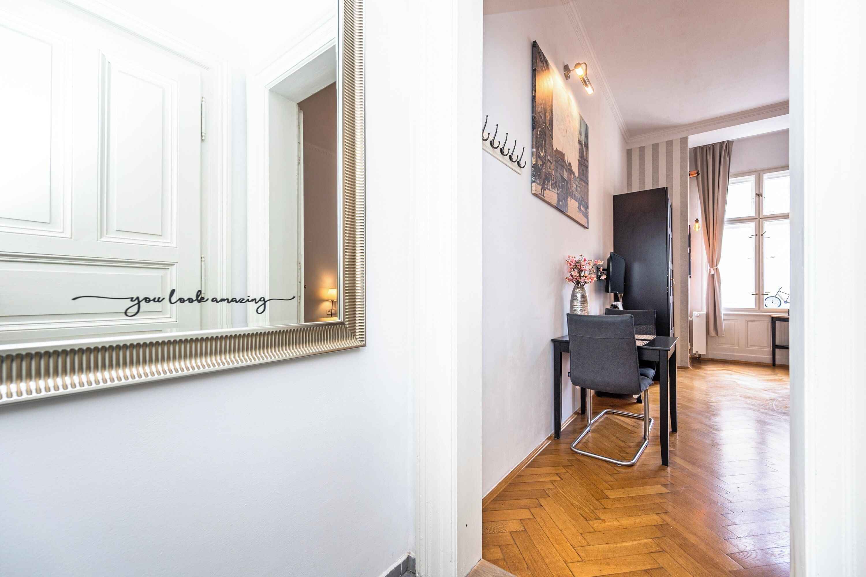 A hallway with a white door, a mirror with a decorative frame, and a wall-mounted sign.