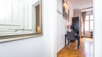 A hallway with a white door, a mirror with a decorative frame, and a wall-mounted sign.