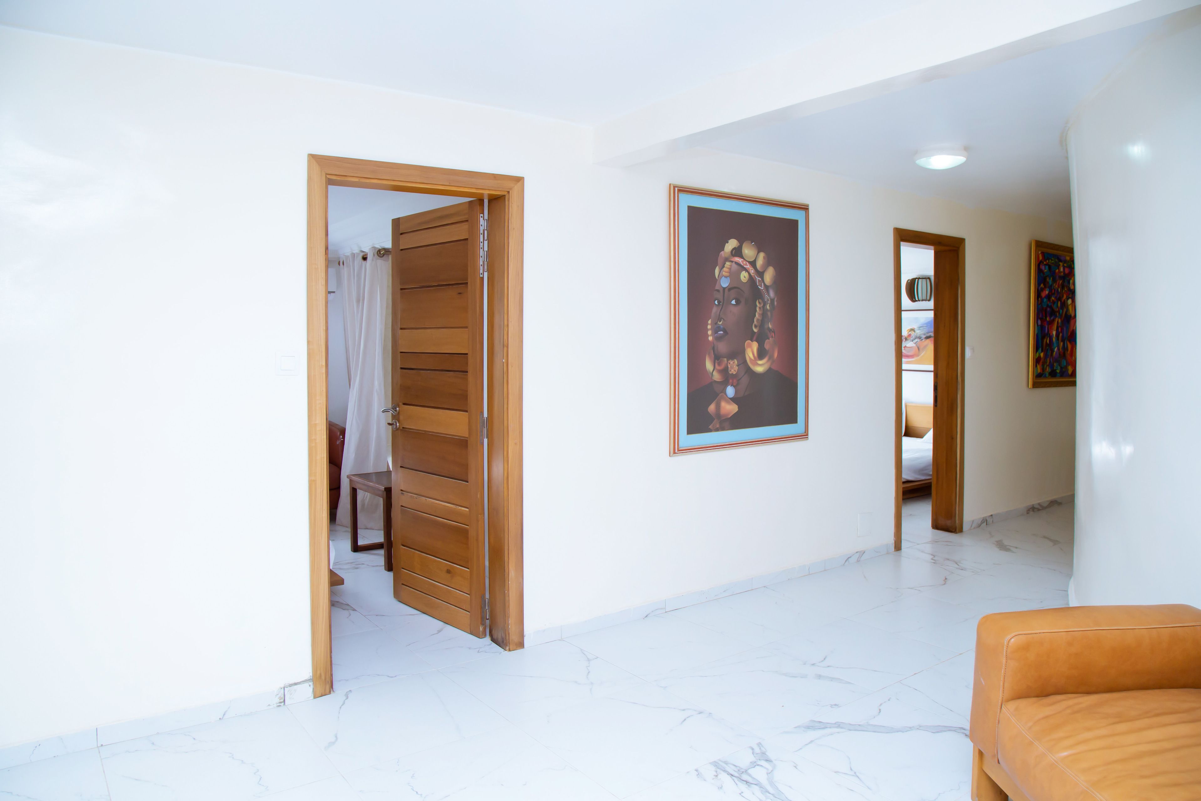 A spacious room with a wooden door, a framed artwork on the wall, and a marble floor.