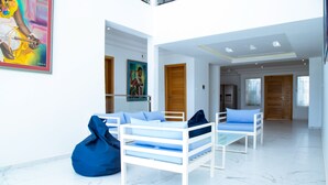 A modern hotel room with white furniture, a large window, and a painting on the wall.