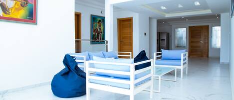 A modern hotel room with white furniture, a large window, and a painting on the wall.