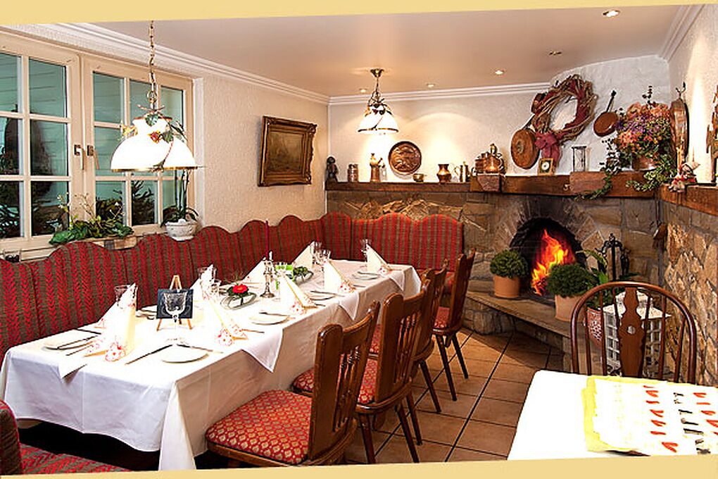 A dining room with a fireplace, a table set for a meal, and a bench along the wall.