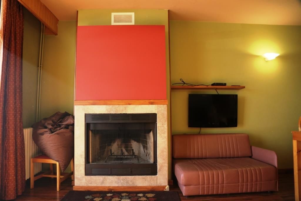 A living room with a fireplace, a sofa, and a television mounted on the wall.