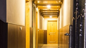 A corridor with wooden walls and a tiled floor, leading to a door at the end.