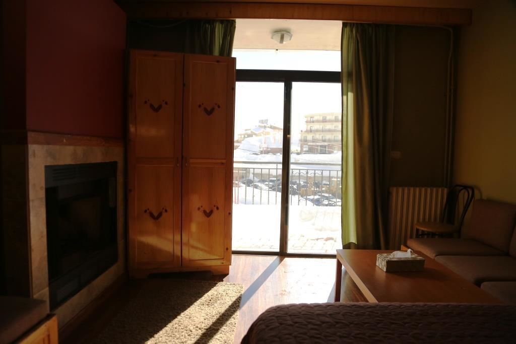 Una habitación con chimenea, un sofá, una mesa y vistas a un paisaje nevado a través de un ventanal corredero.